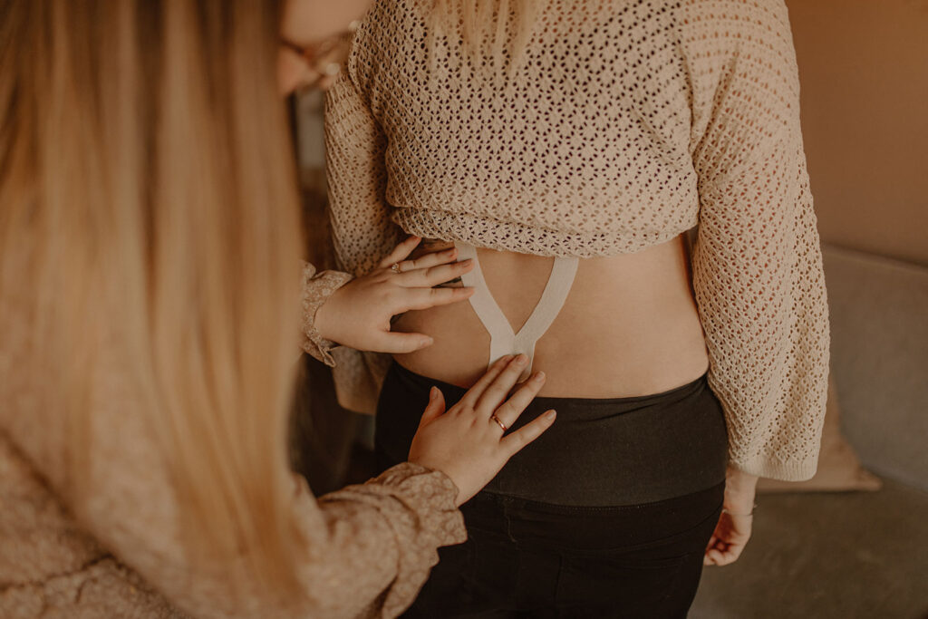 Hebamme macht Kinesiotaping am Rücken einer Frau