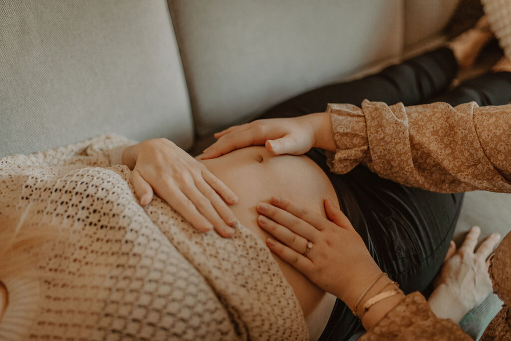 Hände tasten einen schwangeren Bauch ab